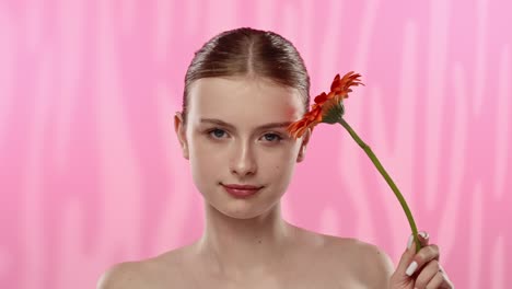 young woman with bright orange flower on vibrant background a serene moment of a woman enjoying the scent of a vibrant orange flower eyes closed in relaxation