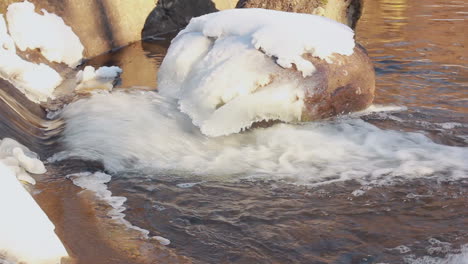 agua de invierno. flujo de agua en invierno. pequeña cascada en invierno. nieve sobre piedras
