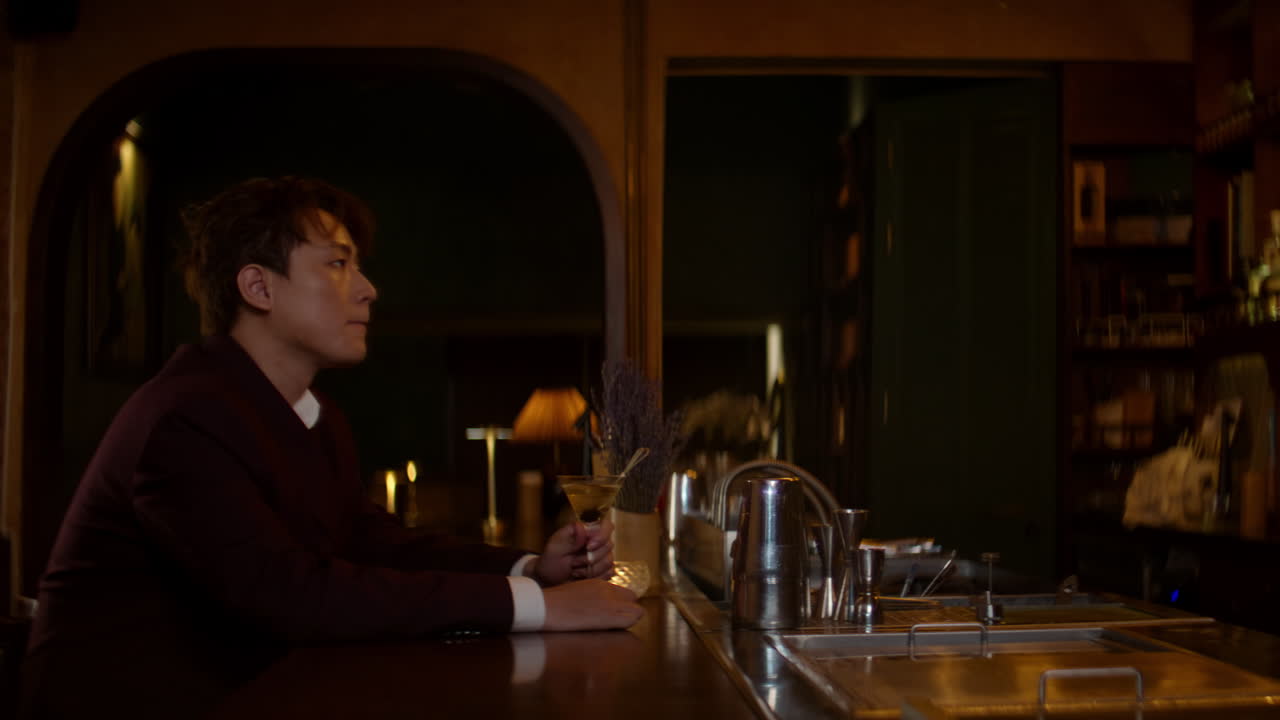 Lonely Asian man sitting at a bar, drinking and reflecting in solitude at night
