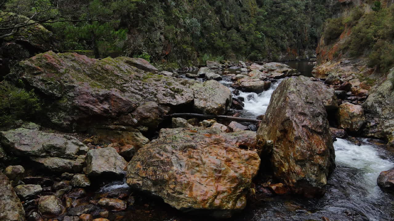 cascada de agua sobre rocas y cantos rodados en la garganta del río rocoso de la montaña de nueva zelanda