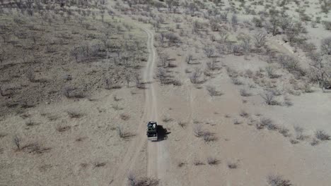 Off-road-car-driving-along-dirt-road-in-Etosha-National-Park-of-Namibia,-Africa