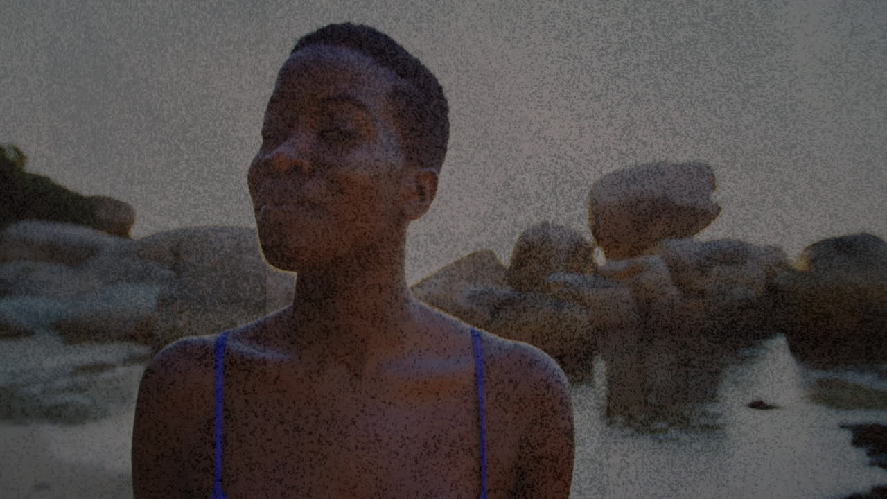Wearing blue swimsuit, woman on rocky beach with textured overlay animation