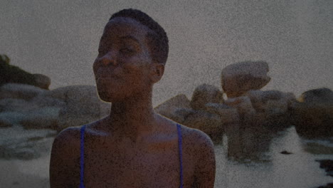 wearing blue swimsuit, woman on rocky beach with textured overlay animation