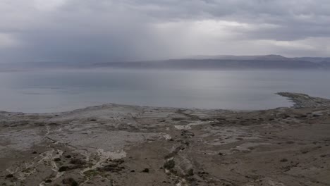 la orilla del mar muerto vuela hacia abajo y se centra en el agua de la inundación, día nublado, israel