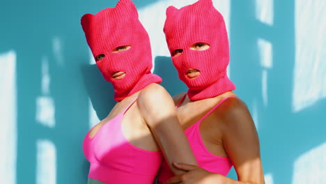 duas mulheres com máscaras de capuz rosa