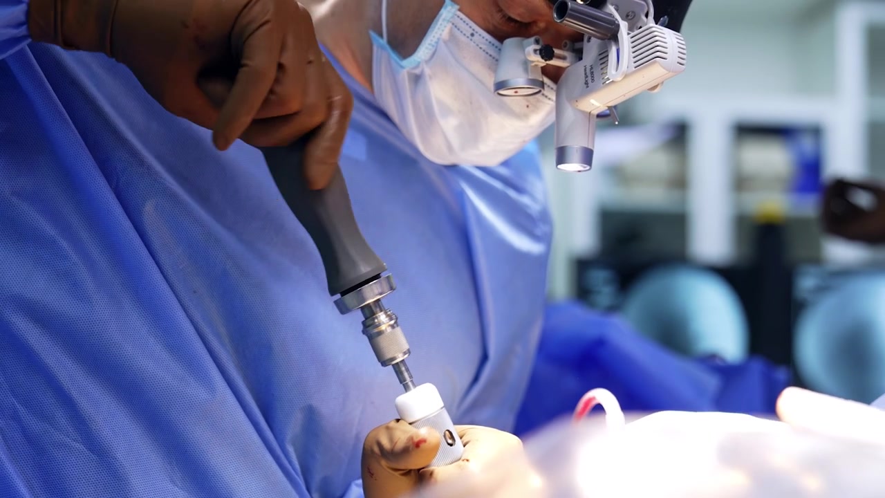 Chirurgo uomo tiene e applica uno strumento medico. Le mani guantate del medico ruotano lo strumento durante l'operazione. Primo piano