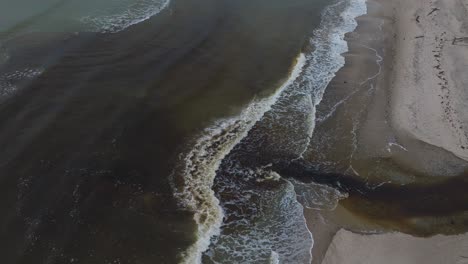 Luftaufnahme-Eines-Kleinen-Dunklen-Flusses,-Der-In-Der-Nähe-Von-Liepaja-In-Die-Ostsee-Mündet,-Weißer-Sandstrand,-Bewölkter-Herbsttag,-Weite-Drohnenaufnahme-Aus-Der-Vogelperspektive,-Die-Sich-Vorwärts-Bewegt