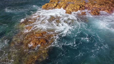 waves of water from the sea hitting the rocks at the seashore in canary island, tenerife, handheld static