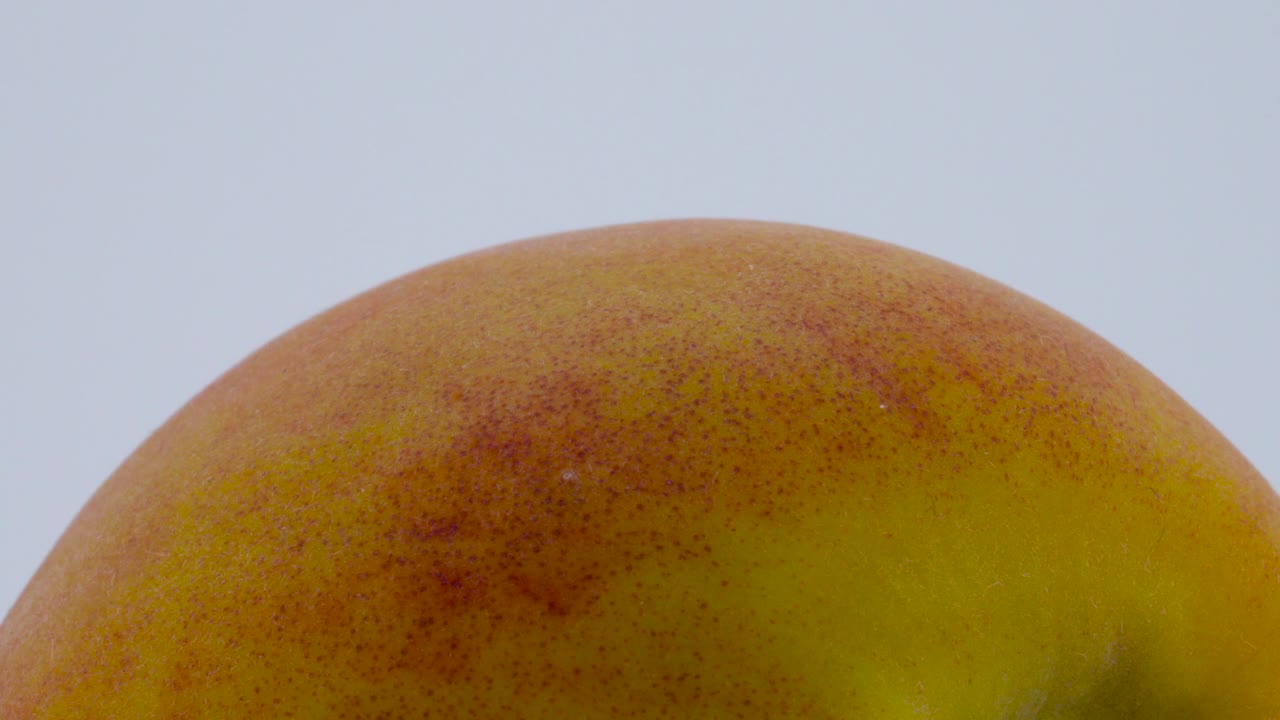 Super close macro of a whole peach fruit. Rotating on the turntable. Isolated on the white background.