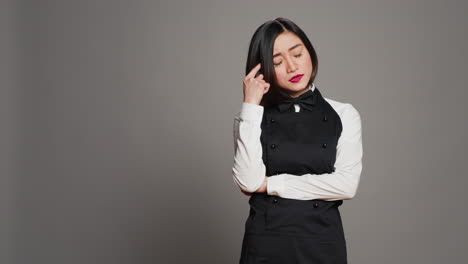 restaurant hostess being thoughtful over grey background