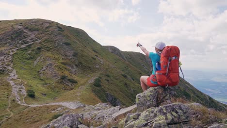 Rucksacktouristin-Zeigt-Die-Richtung-Auf-Dem-Wanderweg-In-Den-Bergen