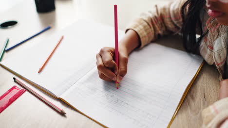 child writing in a notebook with a pencil
