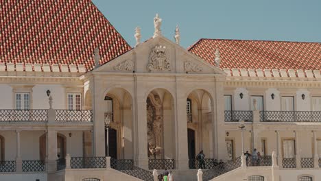 grand facade of coimbra university's historic building, with arched entrances and red tiled roof