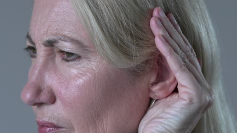 woman closeup cupping ear having difficulty in hearing loss