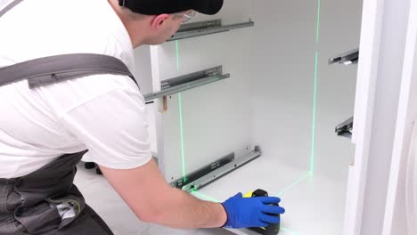 a craftsman in special clothes installs furniture using a laser level a craftsman in special clothes installs furniture using a laser level installation of accessories in the kitchen room home renovation concept video