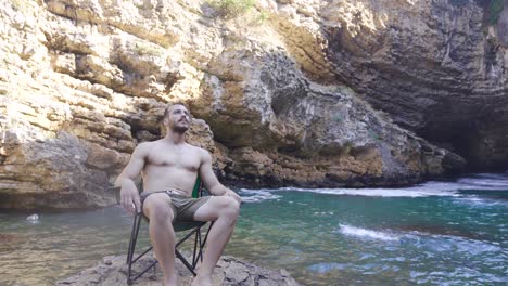 the young man is sitting in his chair at the sea.