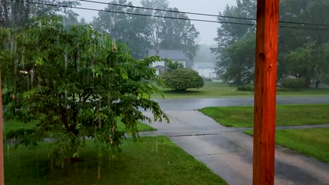 high-quality footage capturing a rainy day from a porch, overlooking a serene neighborhood with lush greenery and wet driveways