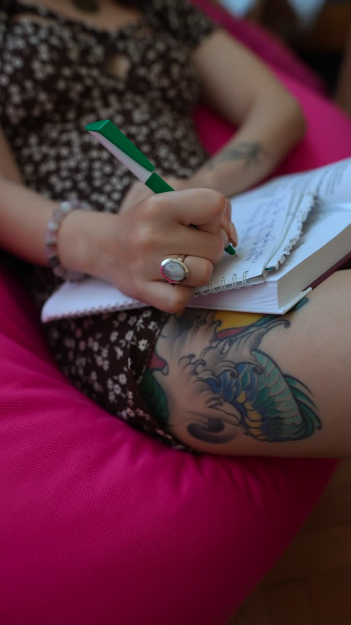 mujer escribiendo en un cuaderno en una bolsa de frijoles rosa