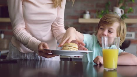 mother serving food to her son at dining table at home 4k