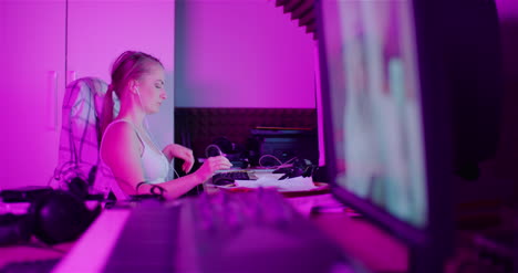 Woman-Browsing-Internet-On-Smartphone-While-Working-On-Computer-At-Home-Office