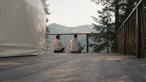 couple meditating in nature, on a mountain with a forest in the background