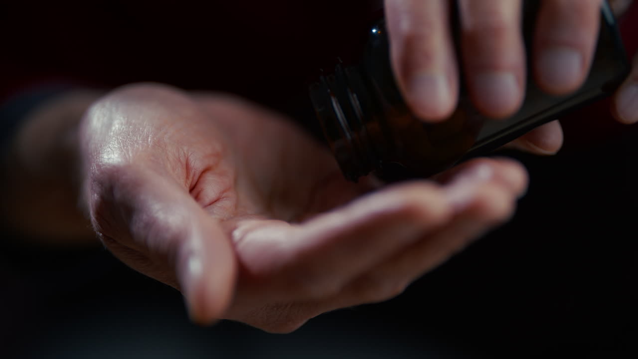 Close-up of Hand Pouring Pills from a Bottle