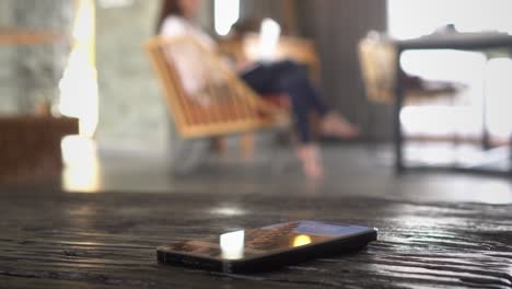 mensaje de texto perdido en el teléfono inteligente con una mujer que trabaja en el fondo en el entorno doméstico