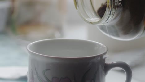 slow motion close-up of a hand holding a glass of coffee spilling into a mug