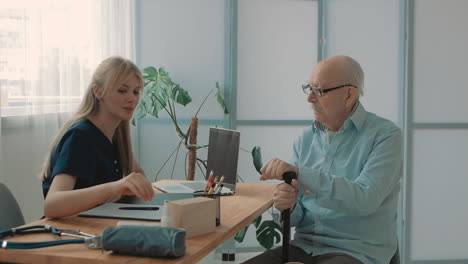 female caring nurse measures the old male temperature with infrared thermometer in the office