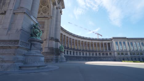 still static shot of the cinquantennaire triumphal arc monument in brussels, belgium, on warm sunny summer day with blue skies, with construction crane above the monument in distance