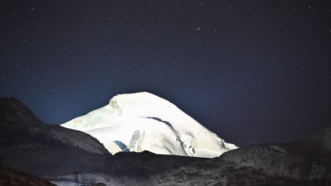 瑞士阿尔卑斯山的冰山后面, 一个星光<unk>溢的蓝色夜晚, 从下面照亮着拖拉机在<unk>轨道