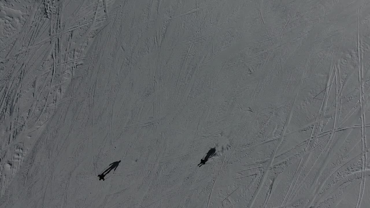 Dronebilde av skiløpere som kjører ned et fjell i de franske Alpene. Solfylt dag
