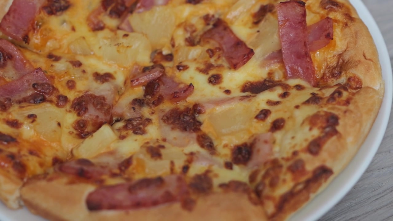 Primo piano di pizza al prosciutto e formaggio appena sfornata, guarnita con formaggio dorato fuso, prosciutto saporito e una crosta dorata e croccante