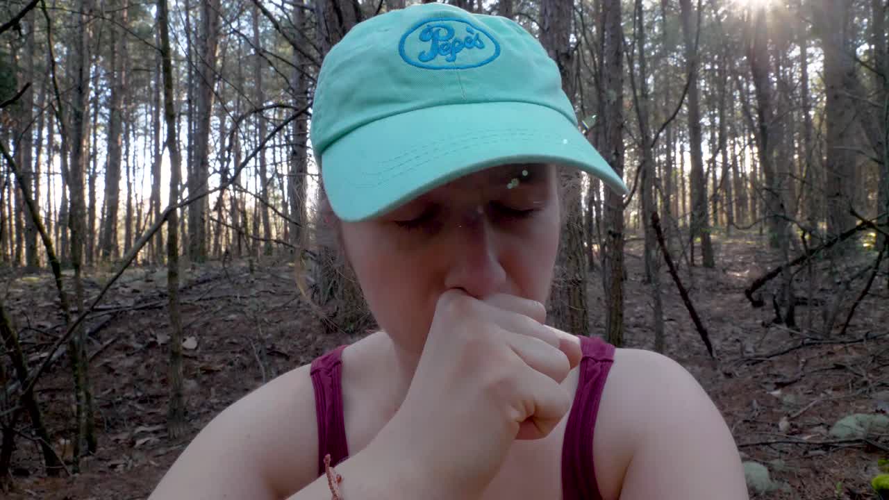 first COVID-19 symptoms: young woman with dry cough in woods, close up slowmo