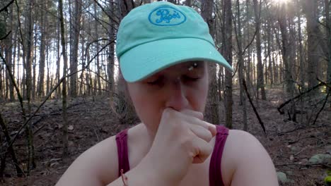 first covid-19 symptoms: young woman with dry cough in woods, close up slowmo