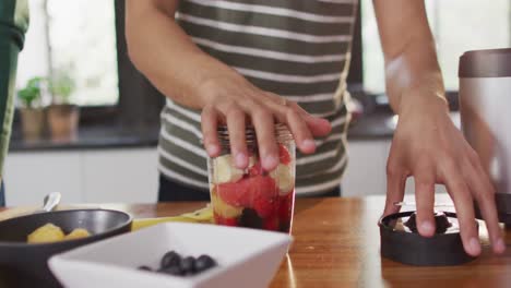 Midsection-of-biracial-man-making-healthy-drink-together-in-kitchen