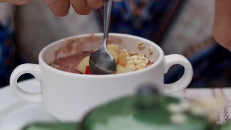 scooping portion from a smoothie oatmeal bowl while chatting during breakfast