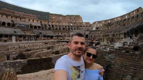 couple taking selfie in colosseum amphitheater in rome, italy