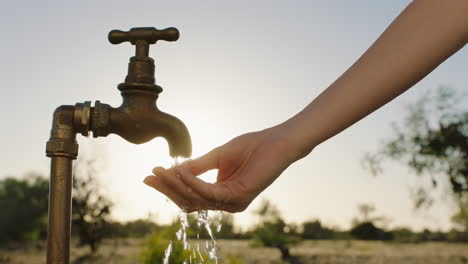 Frau-Wäscht-Sich-Bei-Sonnenaufgang-Auf-Ländlichem-Ackerland-Die-Hände-Unter-Leitungswasser-Mit-Frischem-Wasser