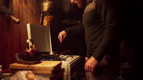 a guy is cooking bacon on the pan at home