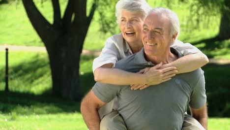 elderly man carrying his aged wife