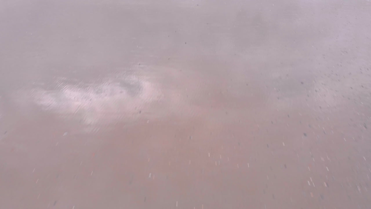 Drone shot of waves rolling onto a sandy beach, capturing the natural rhythm of the ocean