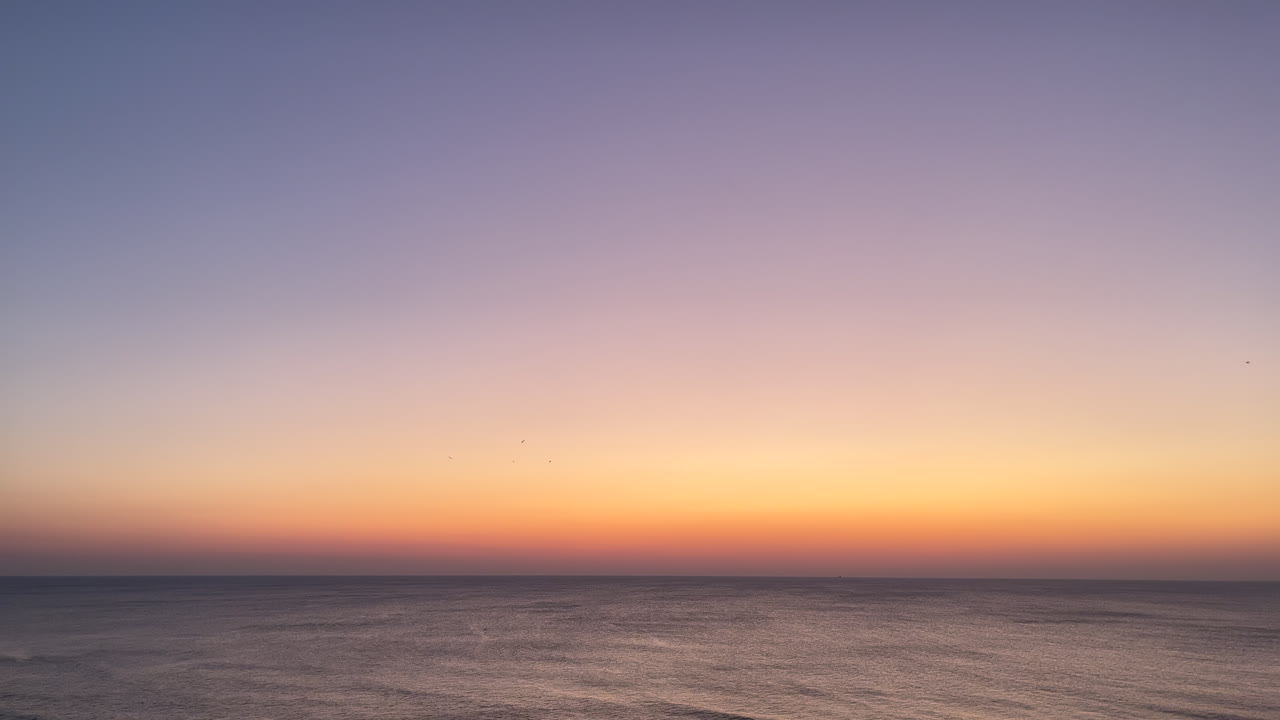 A peaceful sunrise unfolds over the Atlantic at Virginia Beach, featuring soft waves, clear skies, and calm morning ambiance - perfect for intros, backdrops, travel vlog, or relaxation video projects