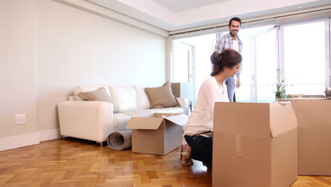 una pareja atractiva desempaquetando cajas en su sala de estar.