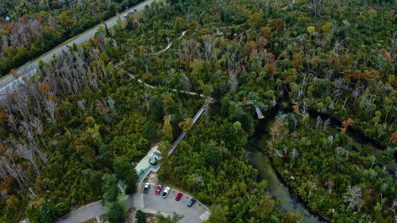 Crystal-blue spring bordered by subtropical forest near Pitt and Sylvan Springs, Florida, featuring surrounding park buildings, walking trails, and river channels framed by autumn foliage