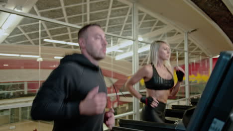 young athletic man and woman exercising and running on treadmill in sport gym