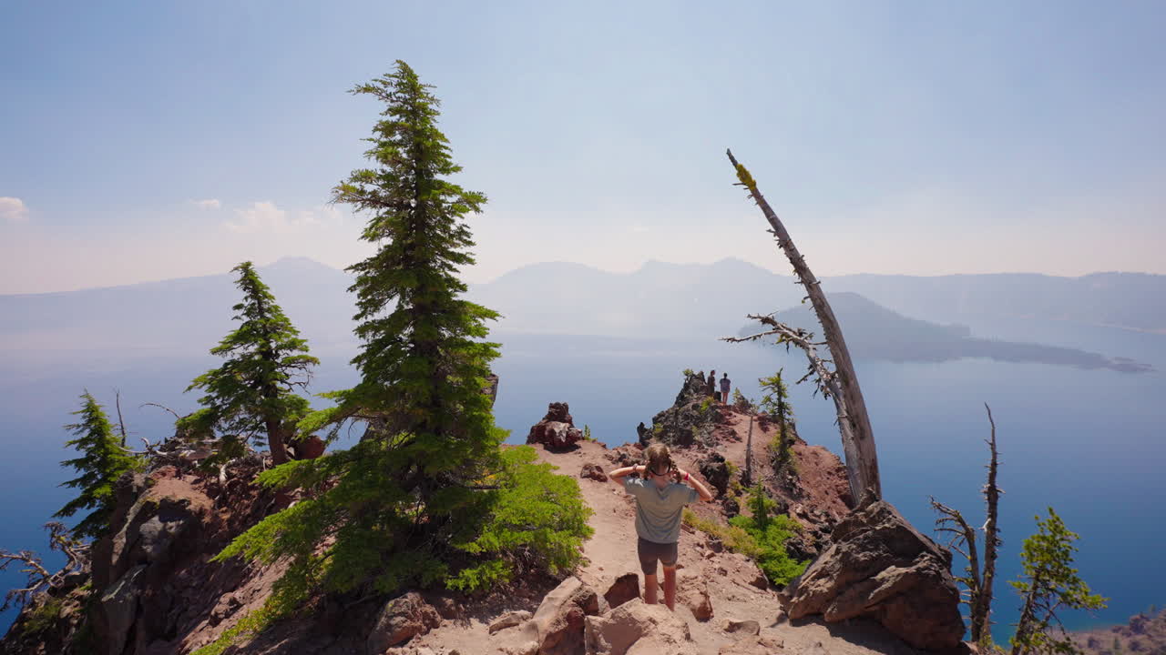People hiking on a scenic trail overlooking a vast lake and mountains