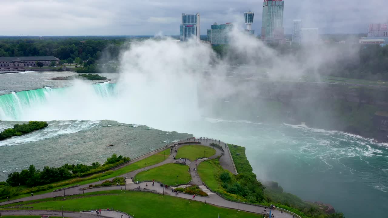 Sweeping aerial of green landscape with winding river flowing toward Niagara Falls horizon, panoramic overview