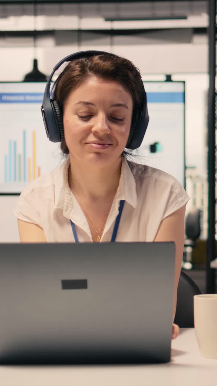 Video verticale. Lavoratrice, musica in cuffia, svago e buon umore, pausa in ufficio.