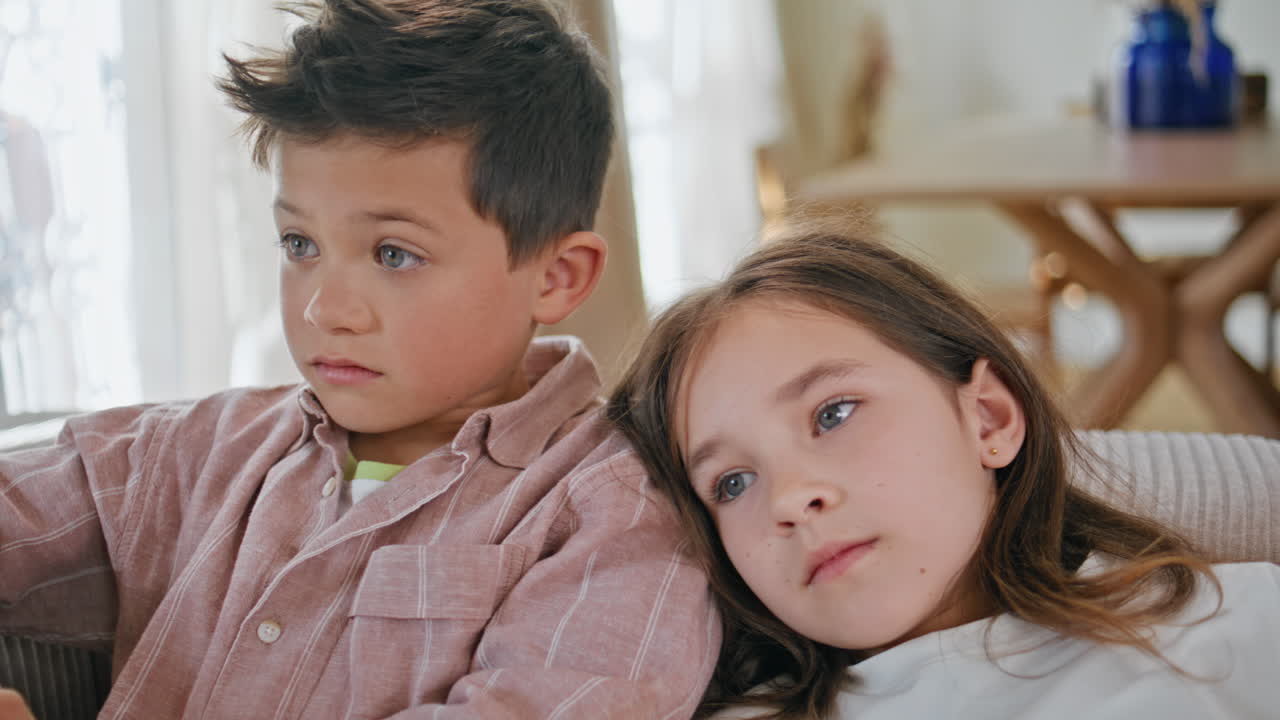 Closeup bonding siblings relaxing at cozy couch. Small children watching cartoon